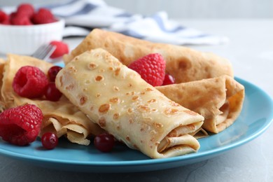 Photo of Delicious crepes served with berries on light grey table, closeup