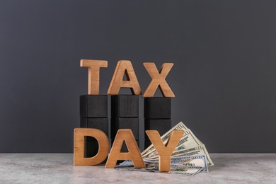 Photo of Phrase TAX DAY, wooden cubes and money on table