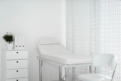 Photo of Examination room with modern couch and folding screen in clinic