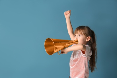 Photo of Cute little girl with megaphone on color background
