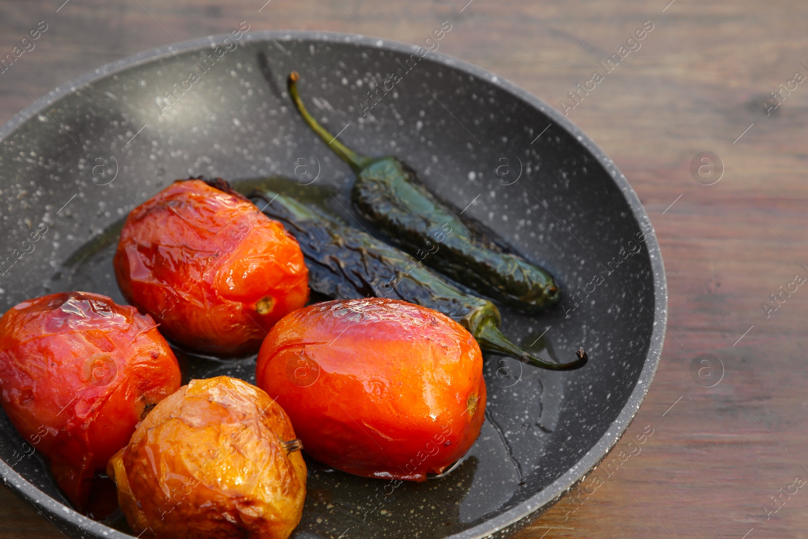 Photo of Frying pan with ingredients for salsa sauce on wooden table, closeup