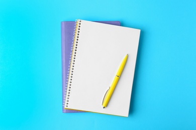 Photo of Notebooks and pen on light blue background, top view