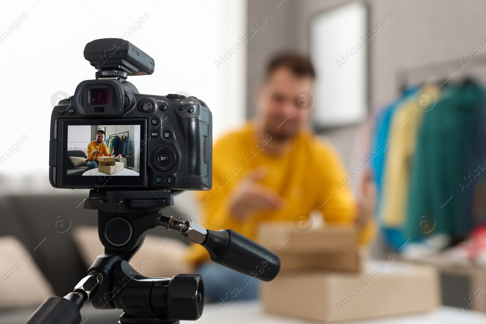 Photo of Fashion blogger with parcels recording video at home, focus on camera