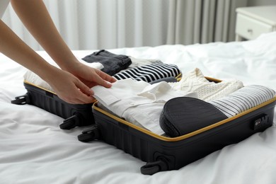 Photo of Woman packing suitcase for trip in bedroom, closeup