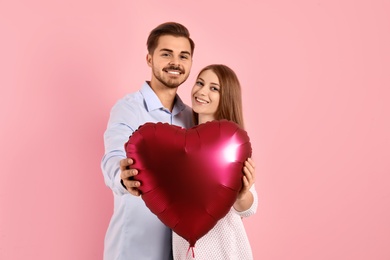 Photo of Portrait of man and woman with heart shaped balloon on color background