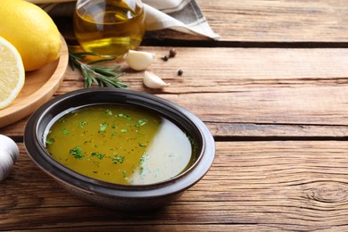 Bowl with lemon sauce and ingredients on wooden table, space for text. Delicious salad dressing