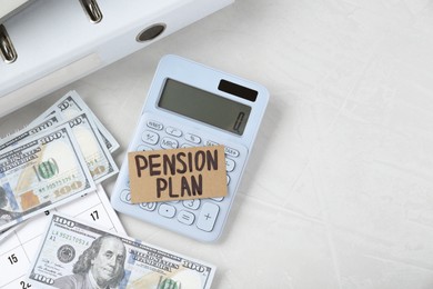 Photo of Card with phrase Pension Plan, dollar banknotes and calculator on white office table, flat lay. Space for text