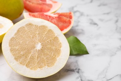 Different sorts of tasty pomelo fruits on white marble table, closeup. Space for text