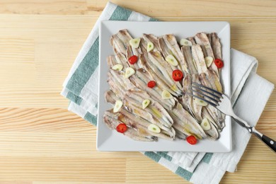 Photo of Tasty pickled anchovies with garlic, chili pepper and fork on wooden table, top view. Space for text