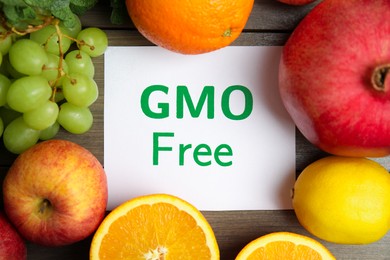 Tasty fresh GMO free products and paper card on wooden table, flat lay