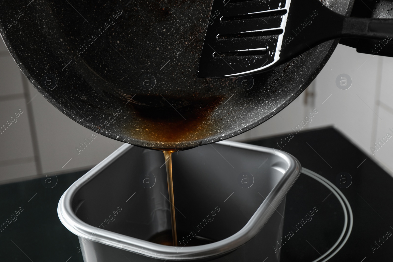 Photo of Pouring used cooking oil from frying pan into container, closeup