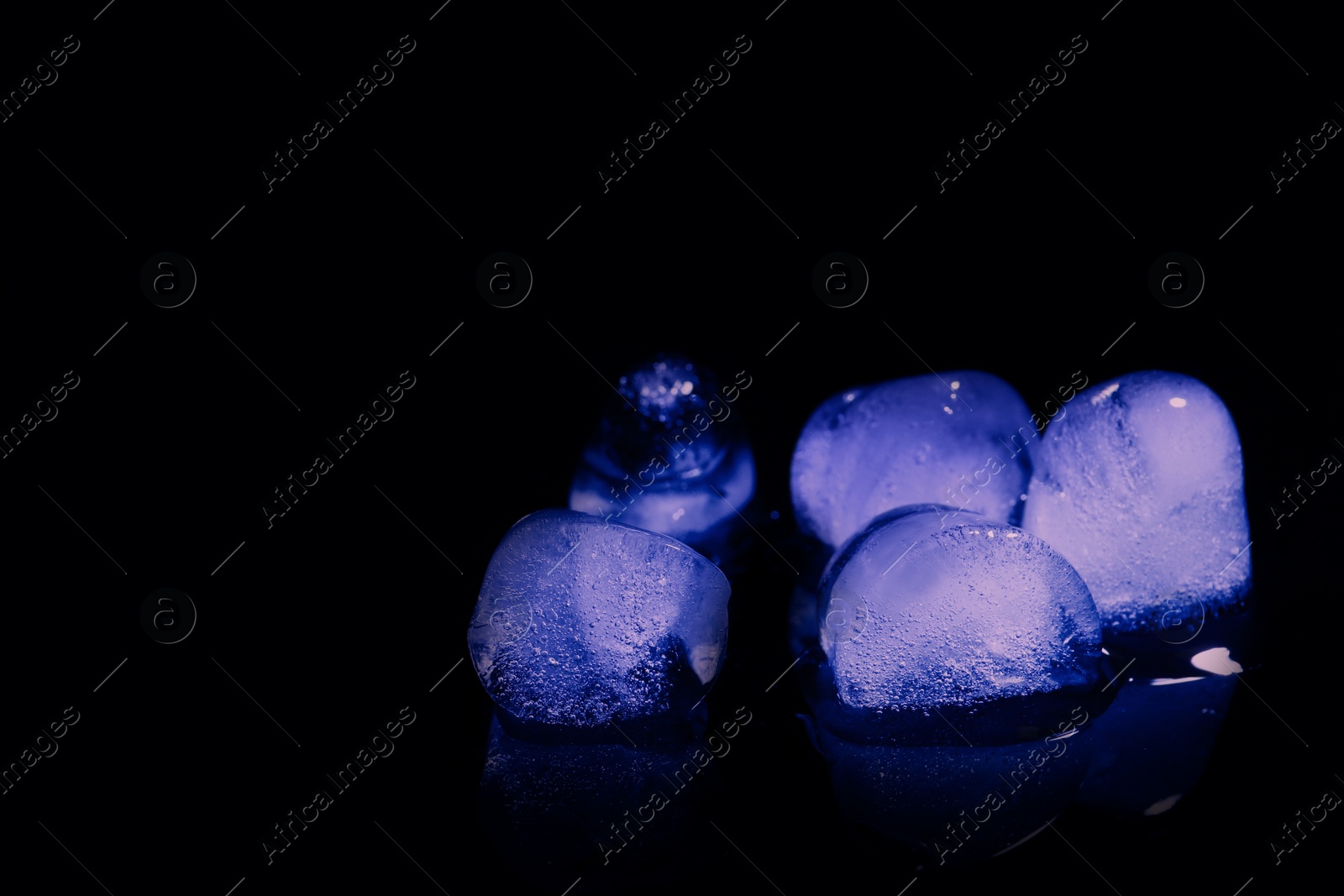 Photo of Melting ice cubes on black background. Space for text