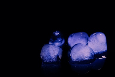 Photo of Melting ice cubes on black background. Space for text