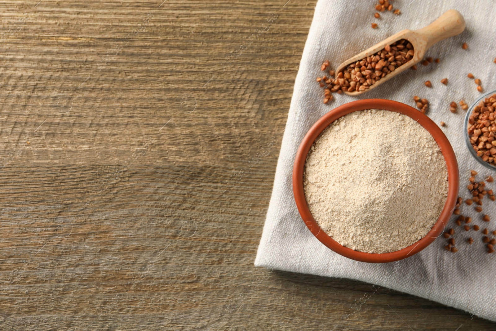 Photo of Buckwheat flour on wooden table, flat lay. Space for text