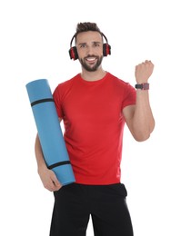 Photo of Handsome man with yoga mat and headphones showing smartwatches on white background