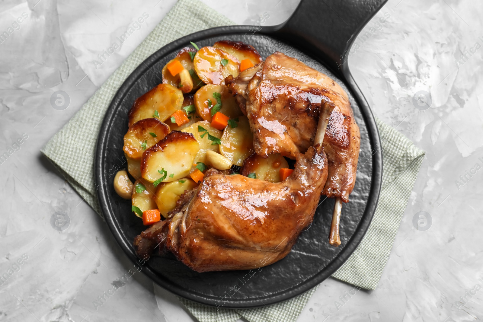 Photo of Tasty cooked rabbit meat with vegetables on light grey table, top view