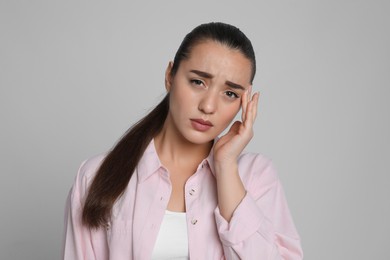 Photo of Young woman suffering from headache on light grey background