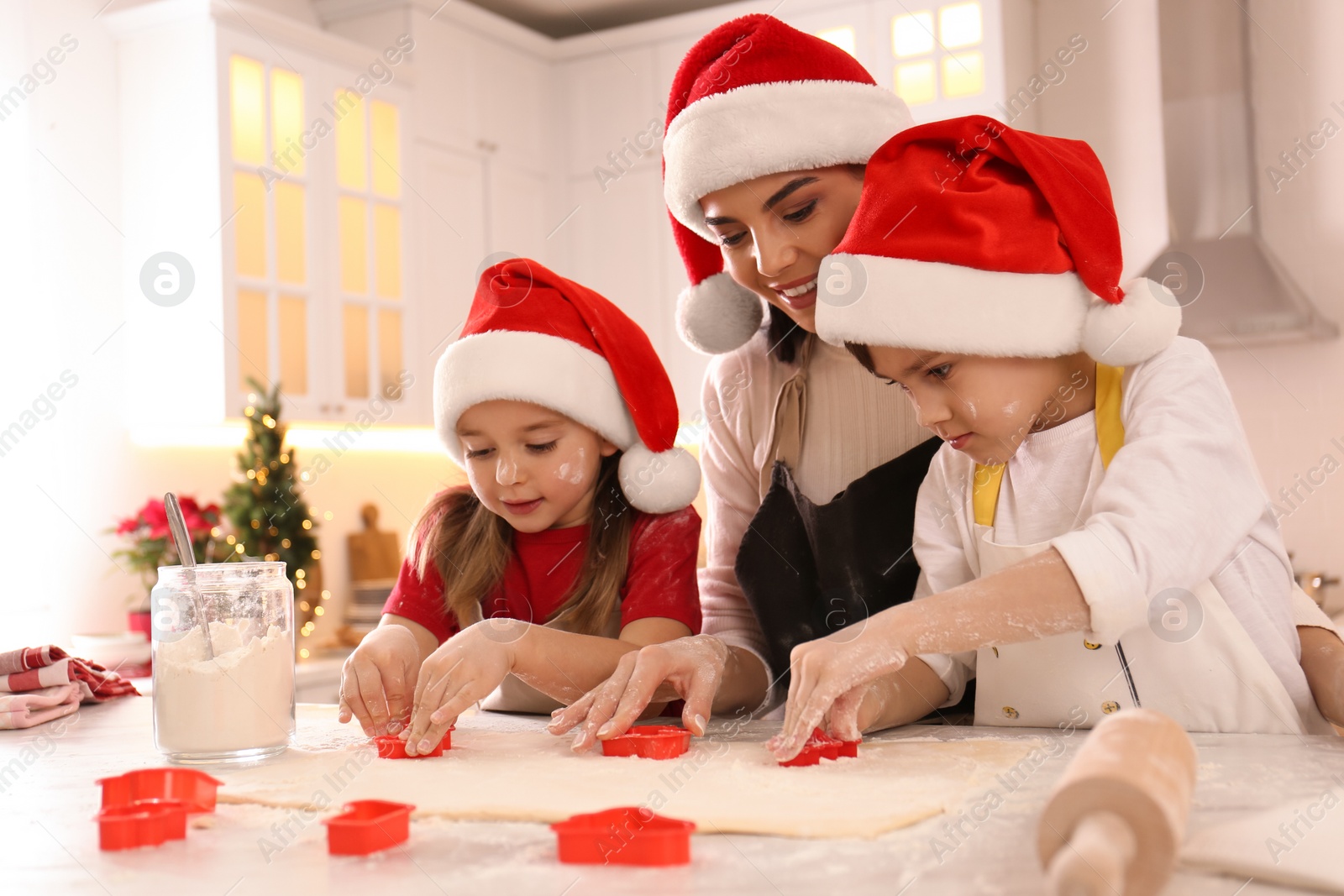 Photo of Mother and her cute little children making Christmas cookies in kitchen