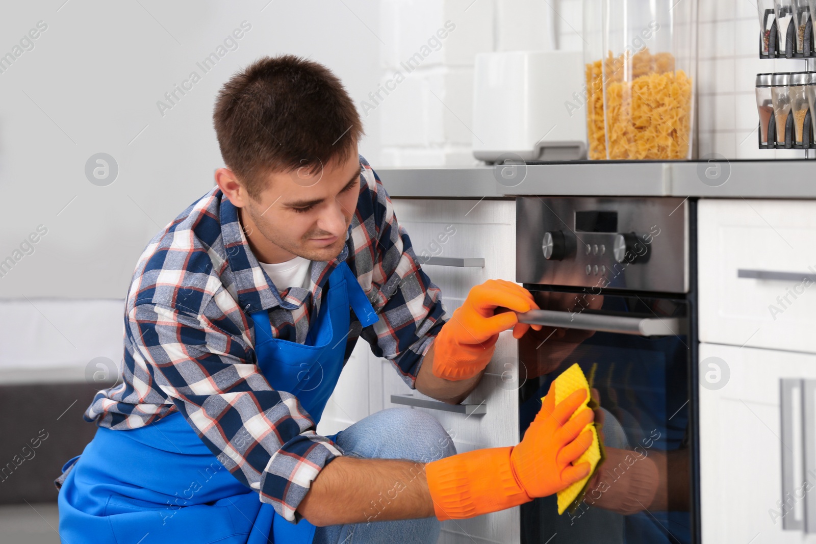 Photo of Man cleaning kitchen oven with rag in house