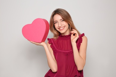 Photo of Portrait of beautiful smiling girl with heart shaped gift box on light background. International Women's Day