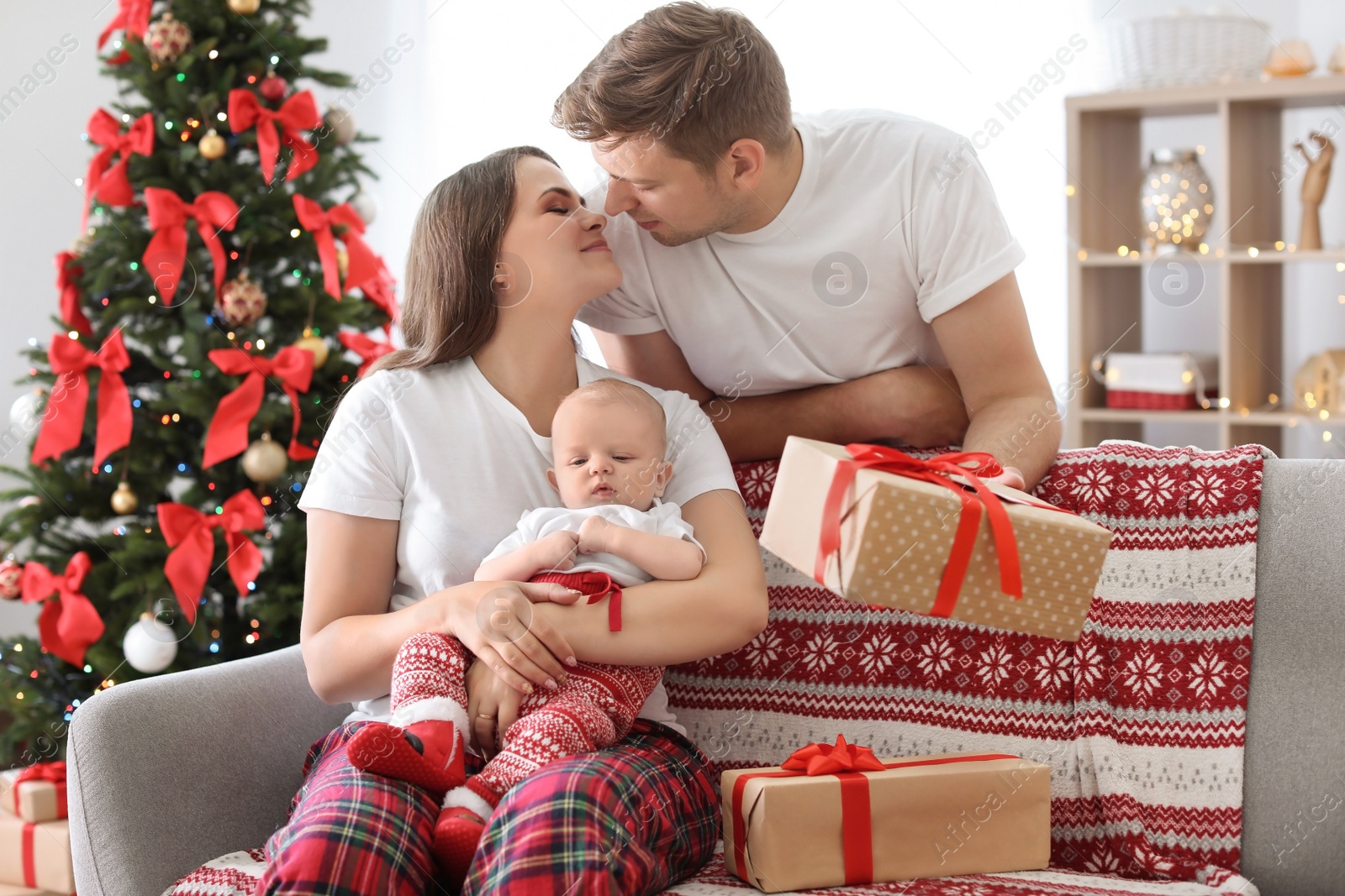 Photo of Happy couple with baby celebrating Christmas together at home