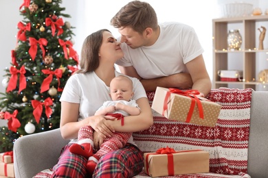 Happy couple with baby celebrating Christmas together at home