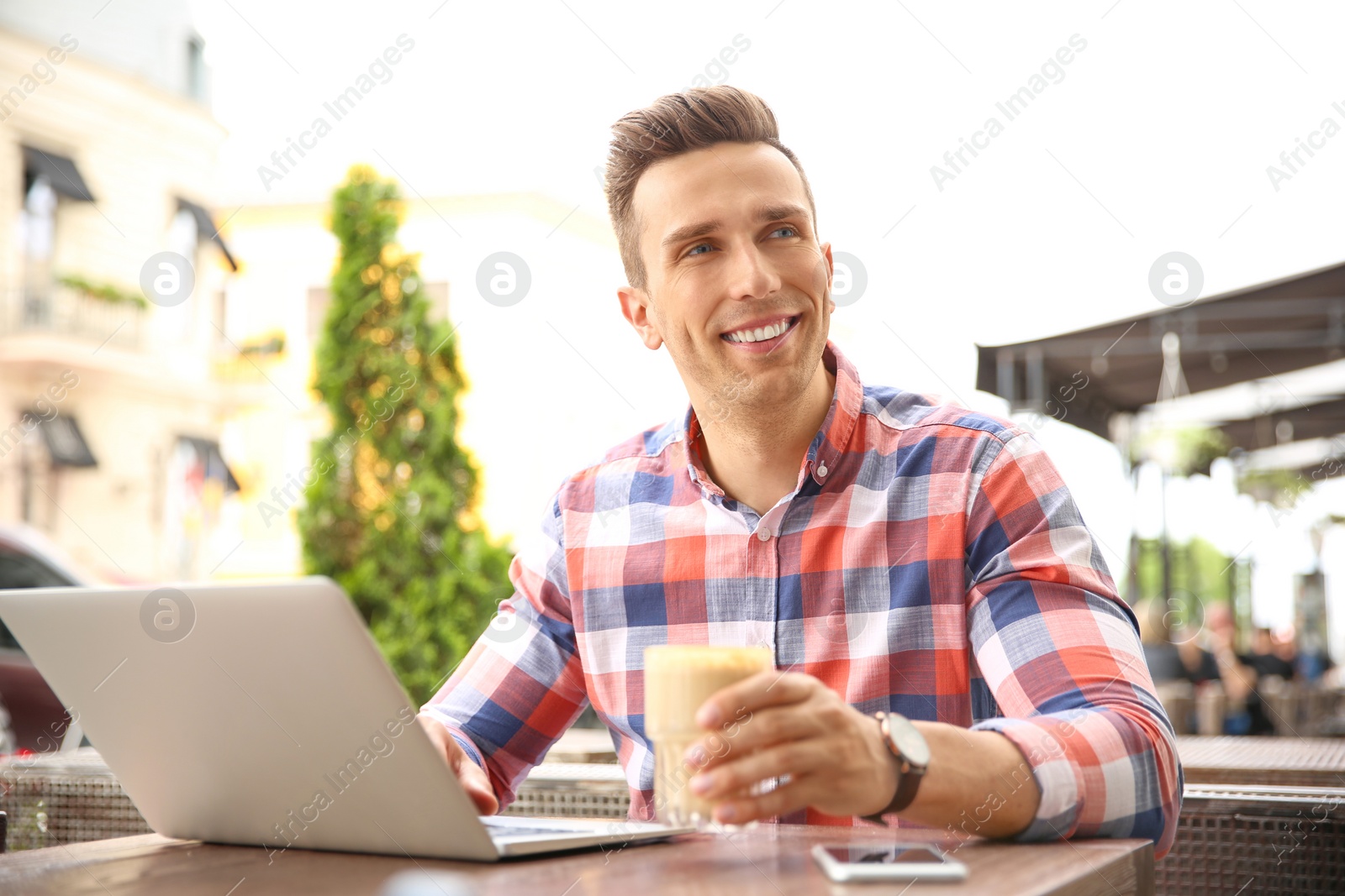 Photo of Young man working with laptop at desk in cafe