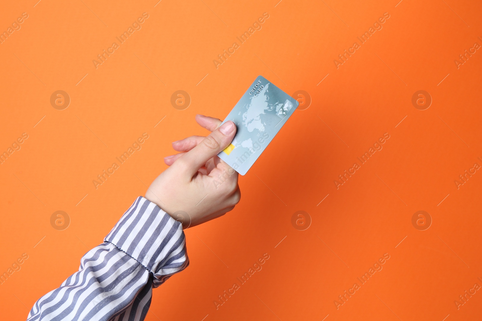 Photo of Woman holding credit card on orange background, closeup