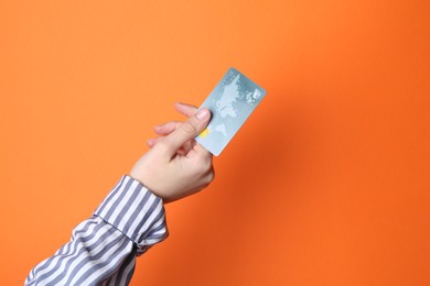 Woman holding credit card on orange background, closeup