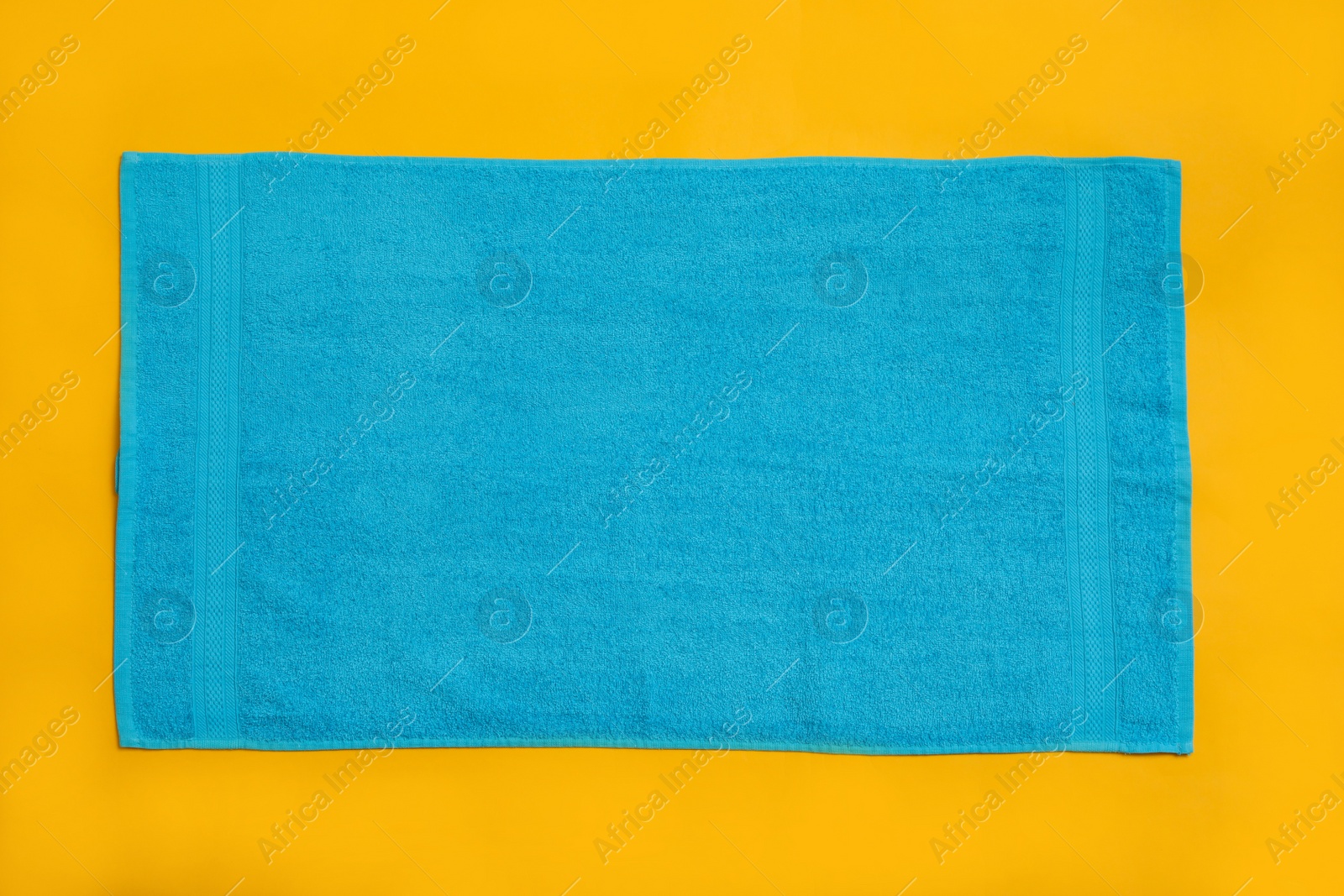 Photo of Light blue beach towel on yellow background, top view