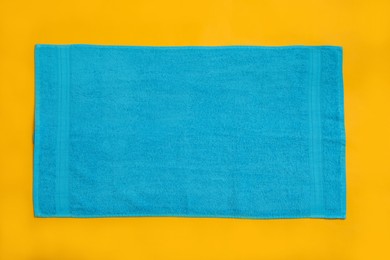 Light blue beach towel on yellow background, top view