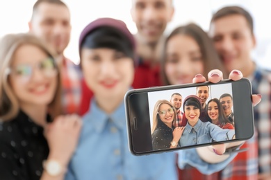 Photo of Happy friends taking selfie indoors