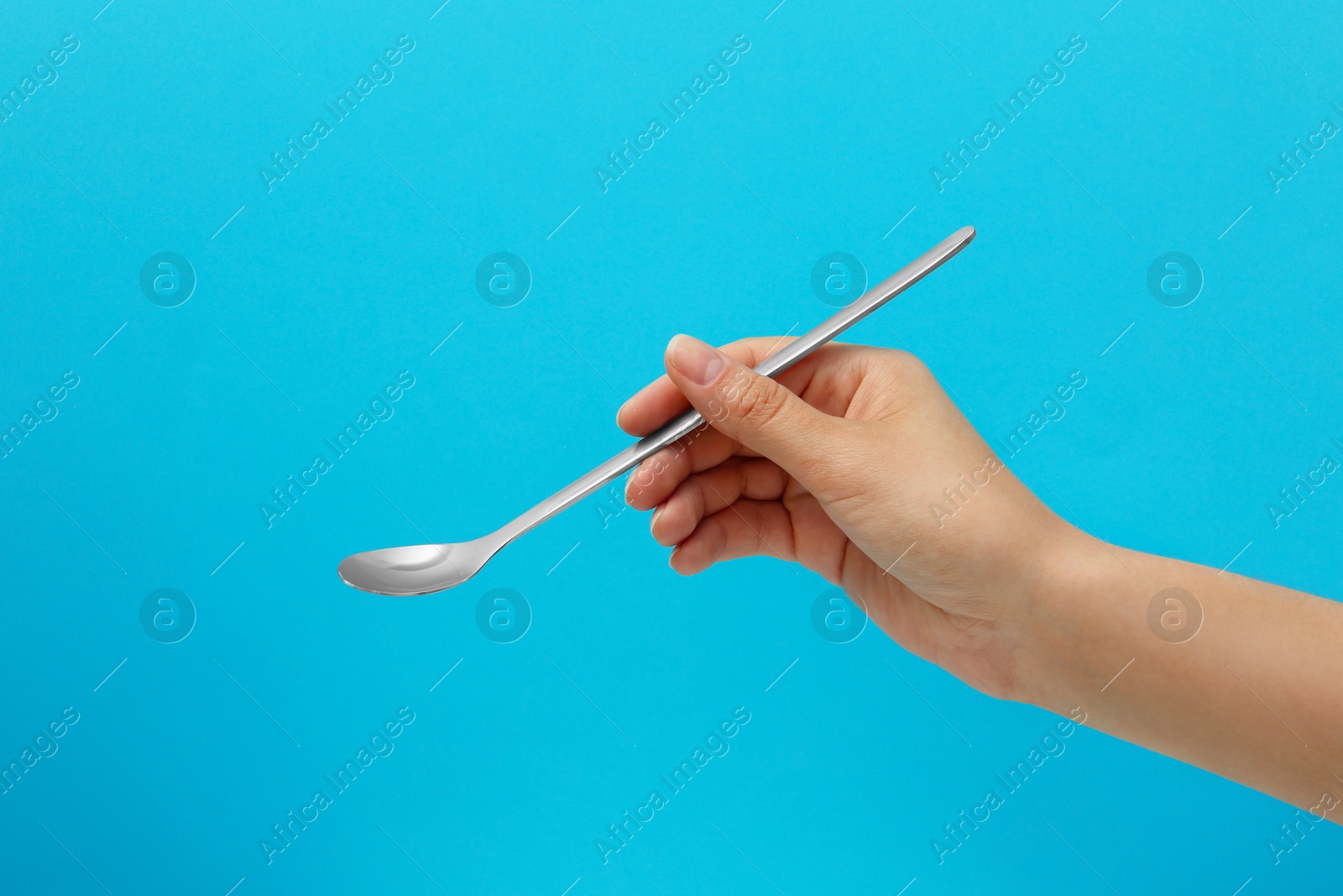 Photo of Woman holding empty soda spoon on color background, closeup