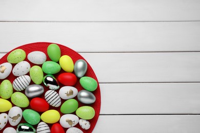 Photo of Many beautifully decorated Easter eggs on white wooden table, top view. Space for text