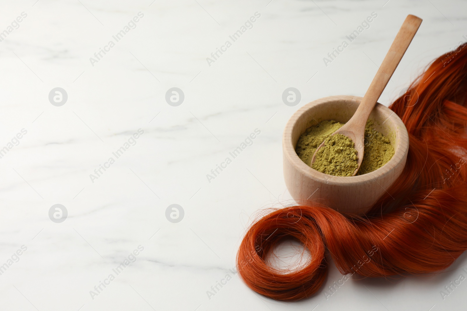 Photo of Bowl of henna powder and red strand on white marble table, space for text. Natural hair coloring