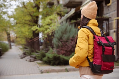 Female tourist with travel backpack on city street. Urban trip