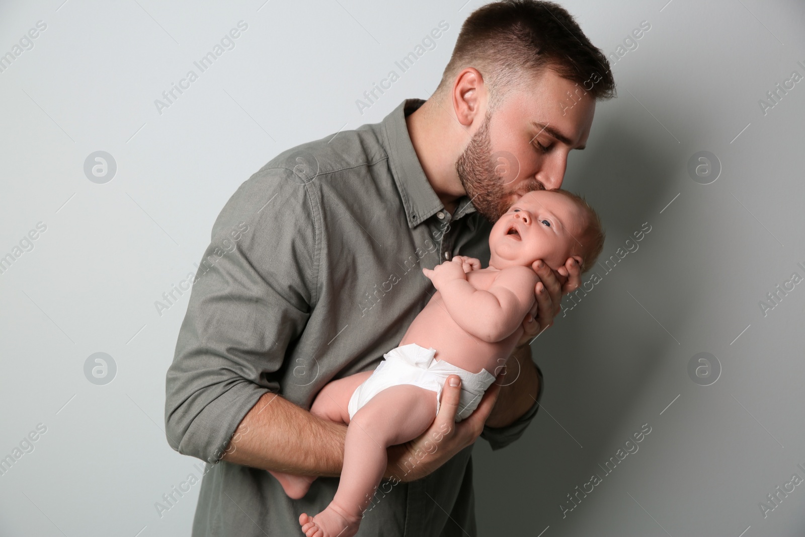 Photo of Father with his newborn son on light grey background