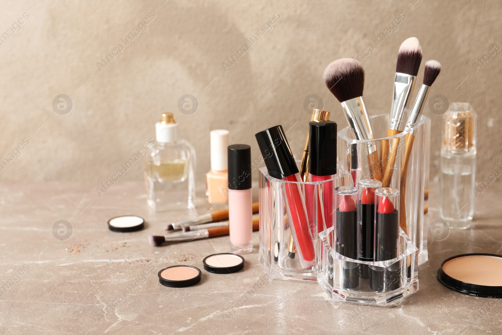 Photo of Lipstick holder with different makeup products on table against color background. Space for text