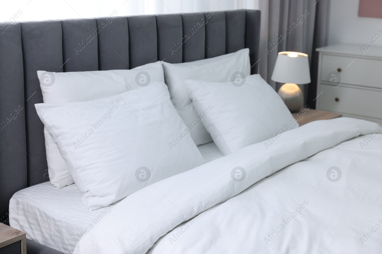 Photo of Soft white pillows and duvet on bed at home