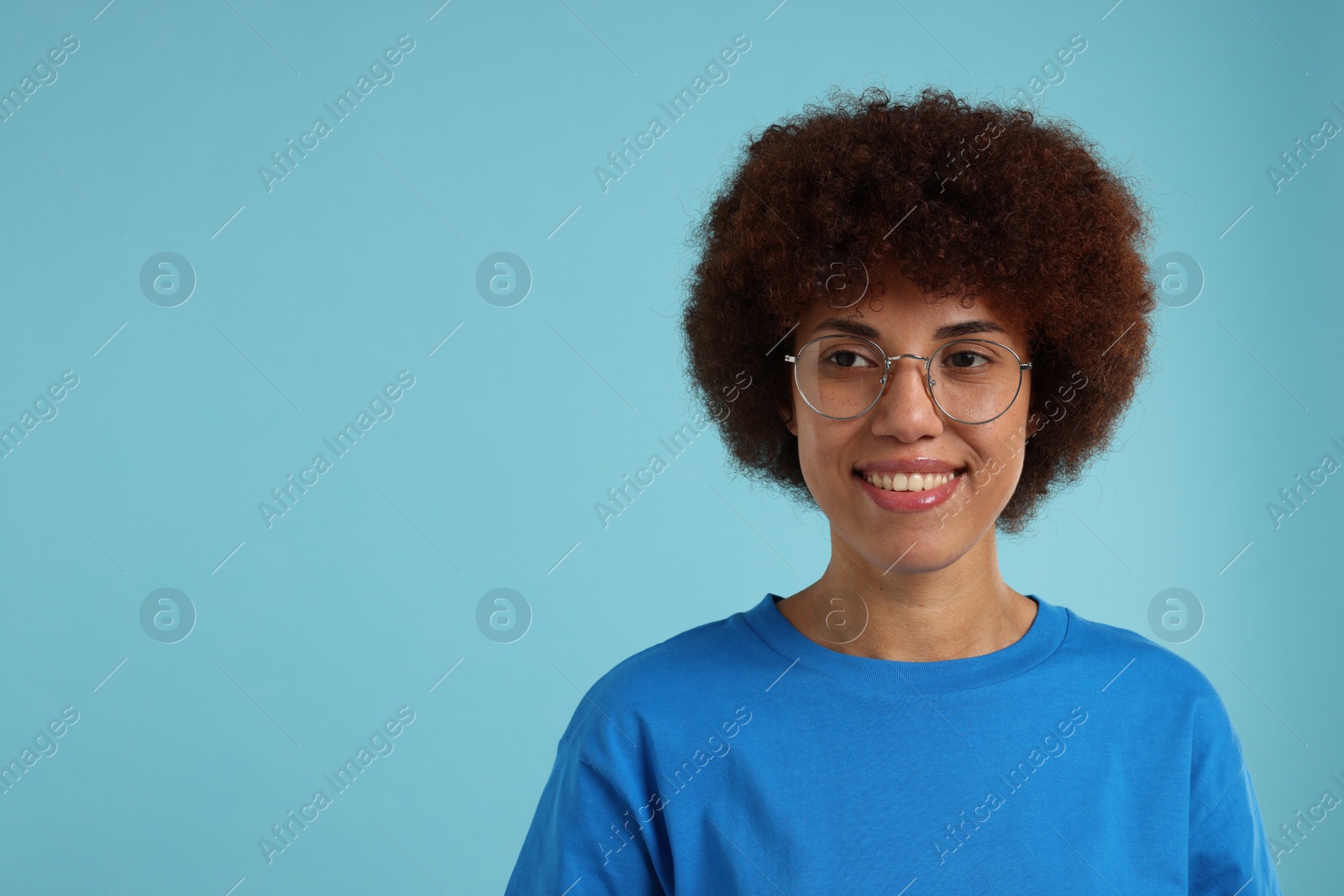 Photo of Portrait of happy young woman in eyeglasses on light blue background. Space for text