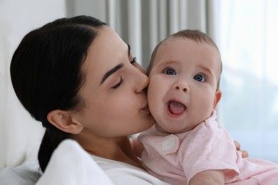 Young mother with her little baby on bed at home