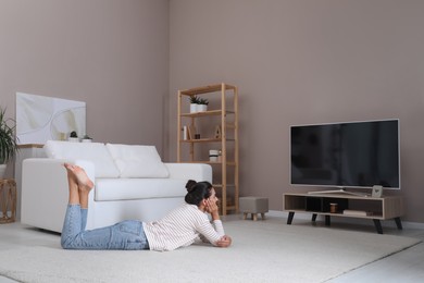 Photo of Woman watching television at home. Living room interior with TV on stand
