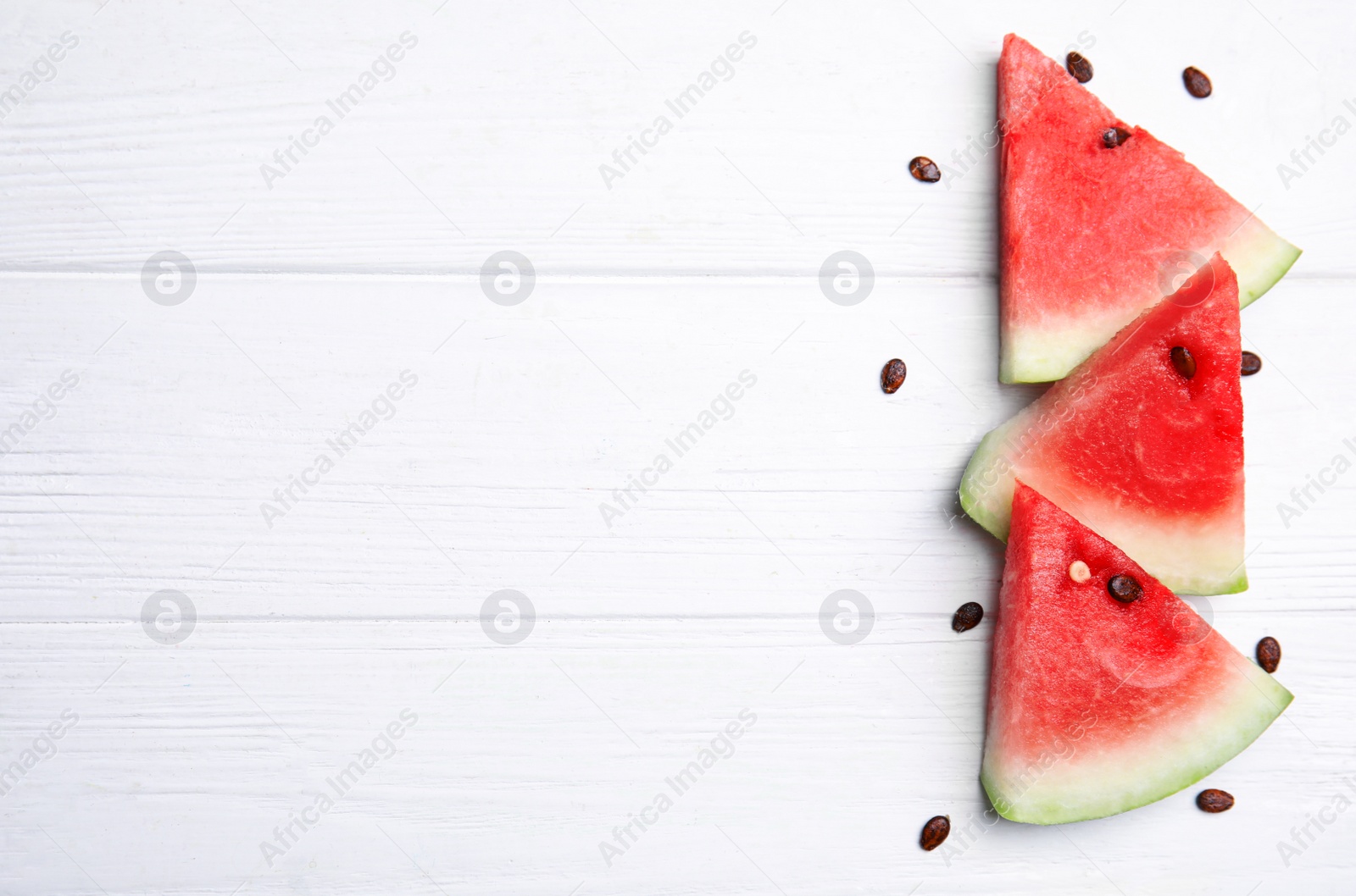 Photo of Watermelon slices on white wooden background, flat lay. Space for text