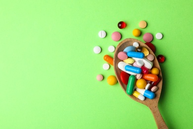 Photo of Spoon and pills on color background, top view with space for text