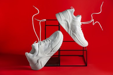 Photo of Stylish presentation of white sneakers on red background