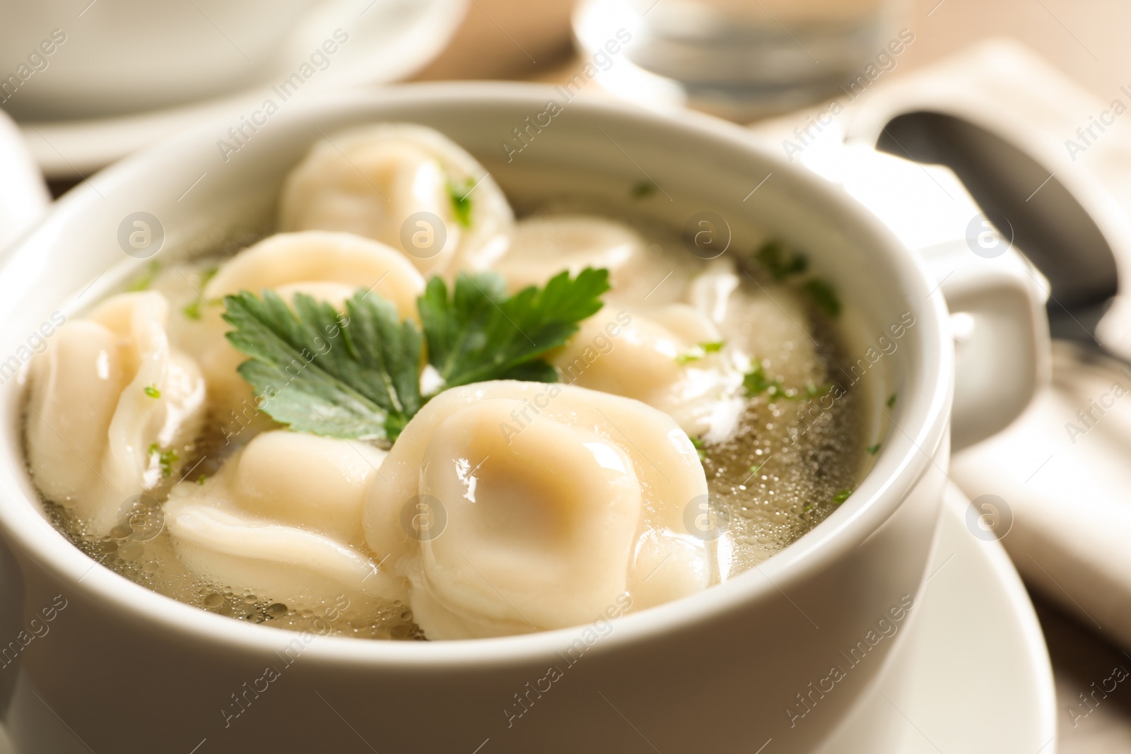 Photo of Bowl of tasty dumplings in broth on table, closeup. Space for text