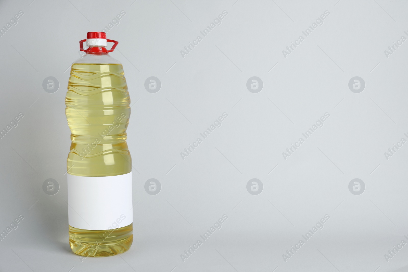 Photo of Bottle of cooking oil on light grey background. Space for text