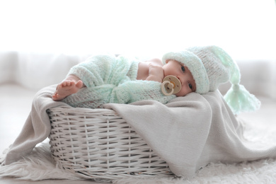 Photo of Cute newborn baby lying on plaid in basket at home