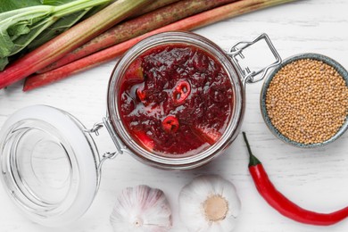 Flat lay composition with tasty rhubarb sauce and ingredients on white wooden table