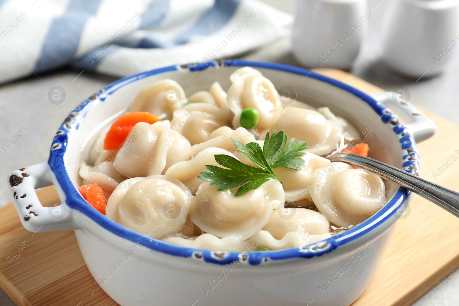 Photo of Bowl of tasty dumplings in broth on table, closeup